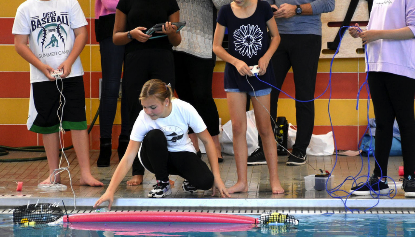 Students testing their robots in a pool.